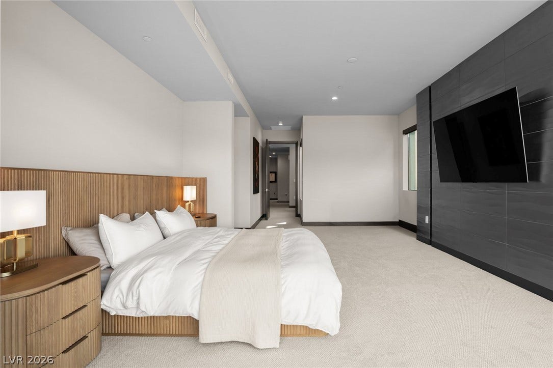 34 Lakefront Drive, Henderson, NV 89011 A spacious bedroom features plush carpeting and a modern textured wall panel.
