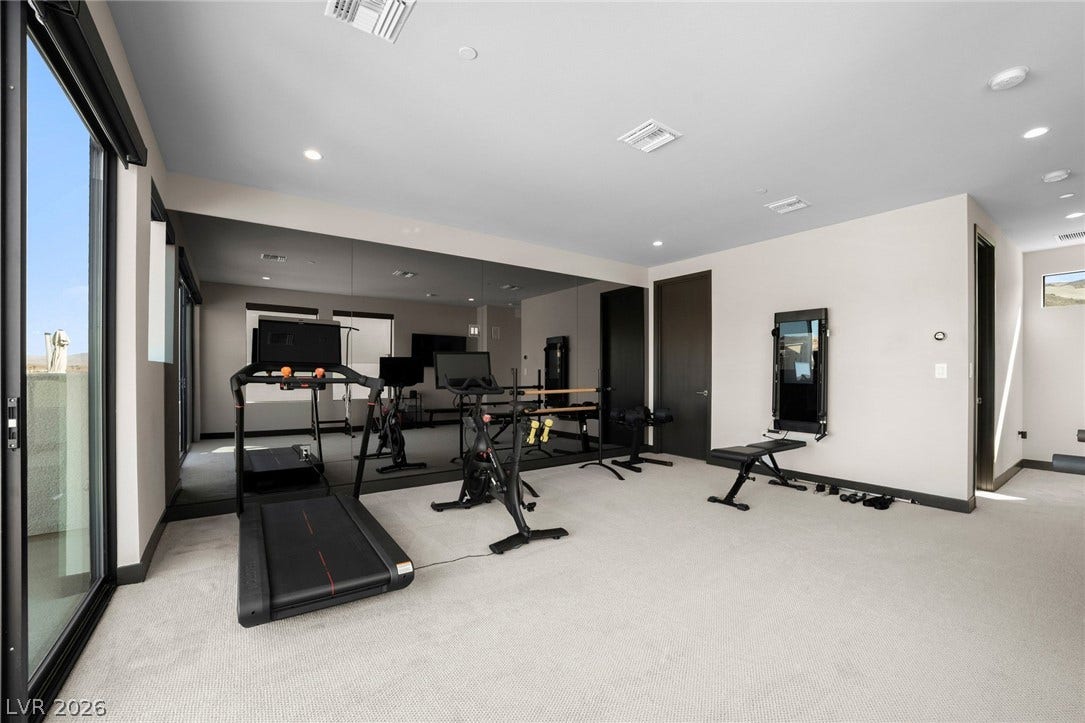34 Lakefront Drive, Henderson, NV 89011 A spacious home gym features plush carpeting, recessed lighting, and a full-wall mirror.