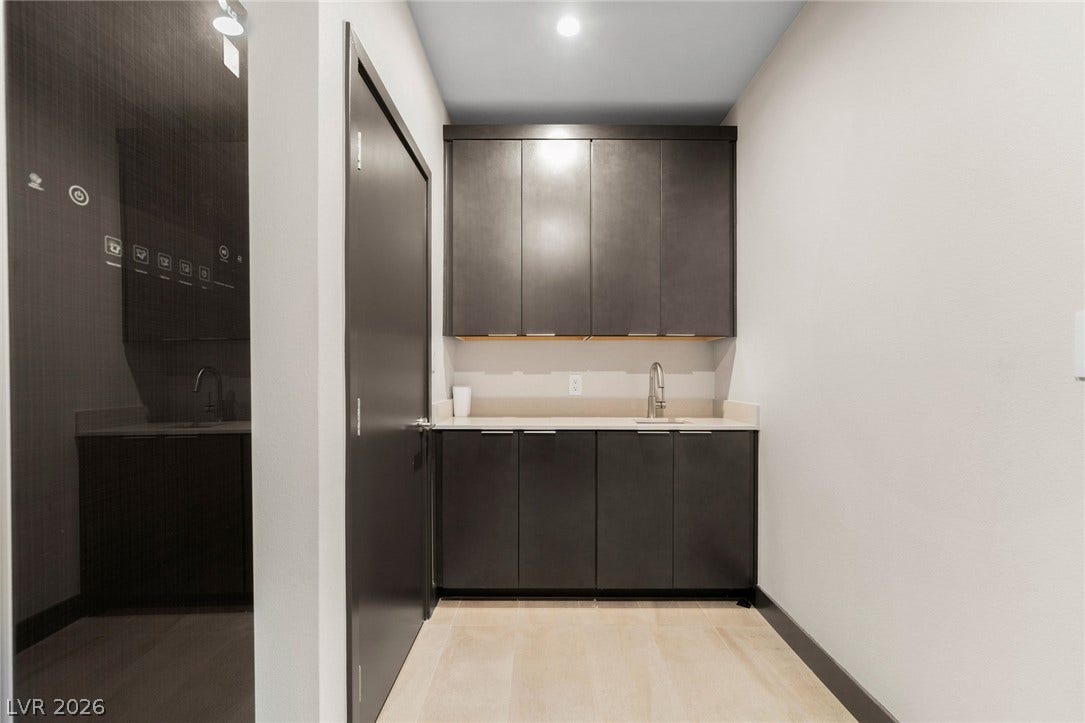 34 Lakefront Drive, Henderson, NV 89011 A sleek modern wet bar features dark minimalist cabinetry under recessed lighting.