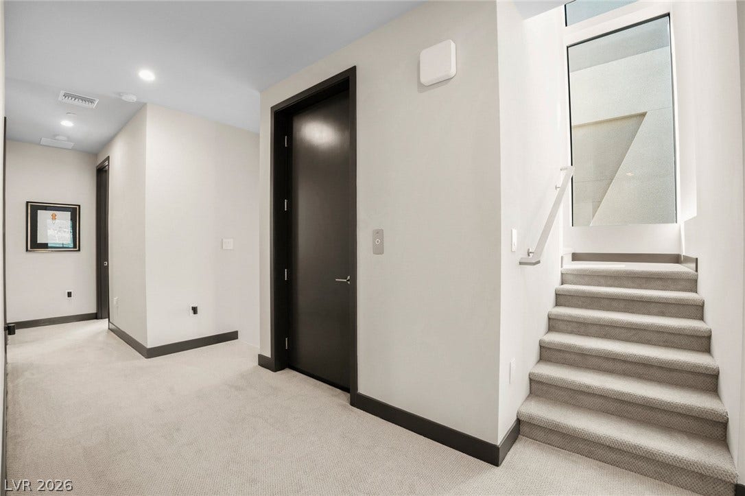 34 Lakefront Drive, Henderson, NV 89011 A modern hallway features clean architectural lines, recessed lighting, and carpeted stairs leading upward.
