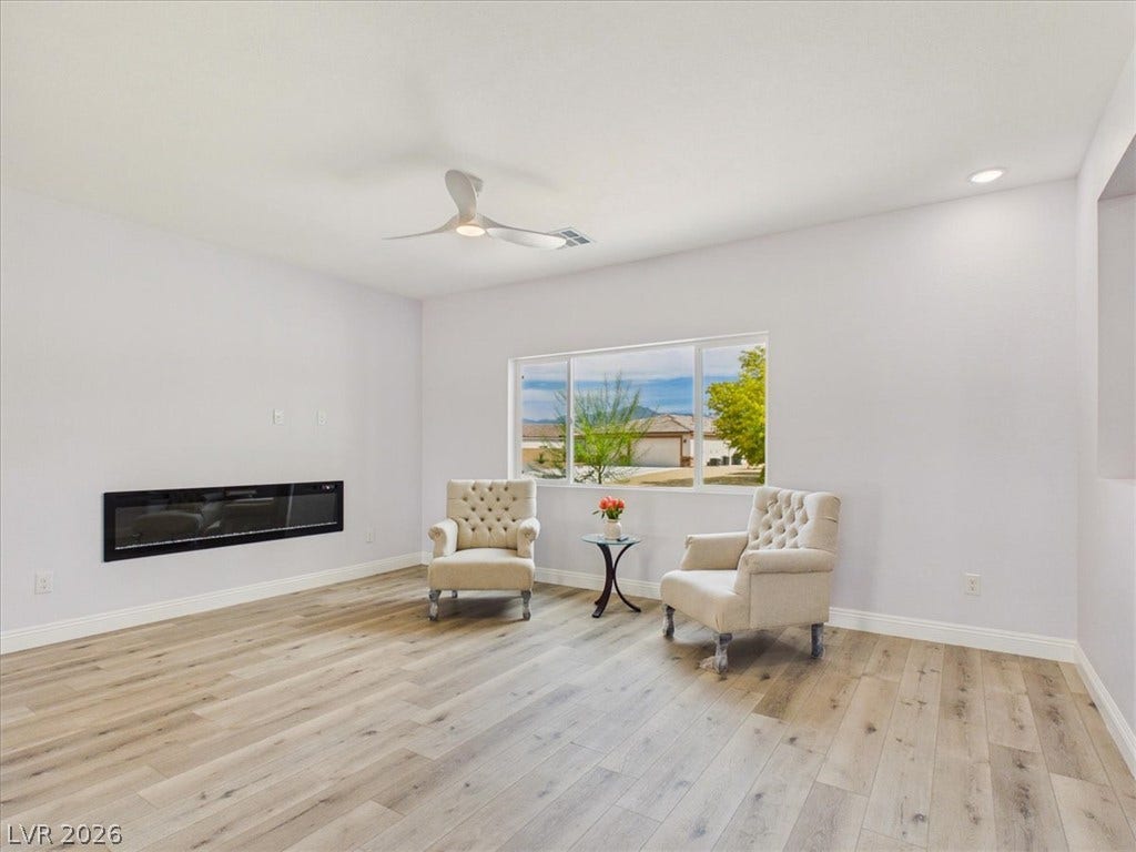 6680 S Raintree Court, Pahrump, NV 89061 Warm wood flooring and a modern fireplace anchor this light-filled living space.