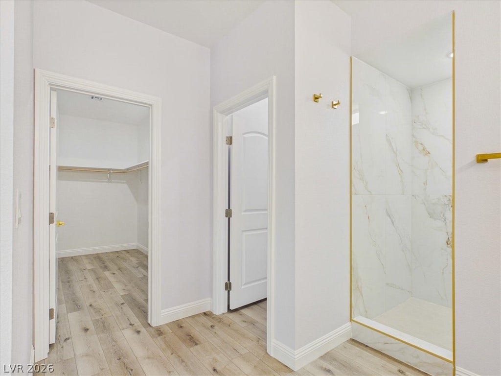 6680 S Raintree Court, Pahrump, NV 89061 Gleaming marble-style shower walls pair beautifully with rich wood-textured flooring.