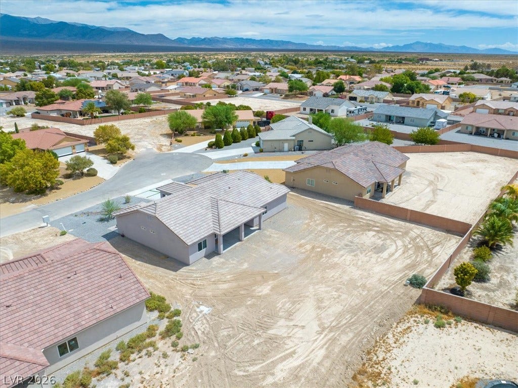 6680 S Raintree Court, Pahrump, NV 89061 Distant mountains frame the surrounding neighborhood of this tile-roofed home under a blue sky.