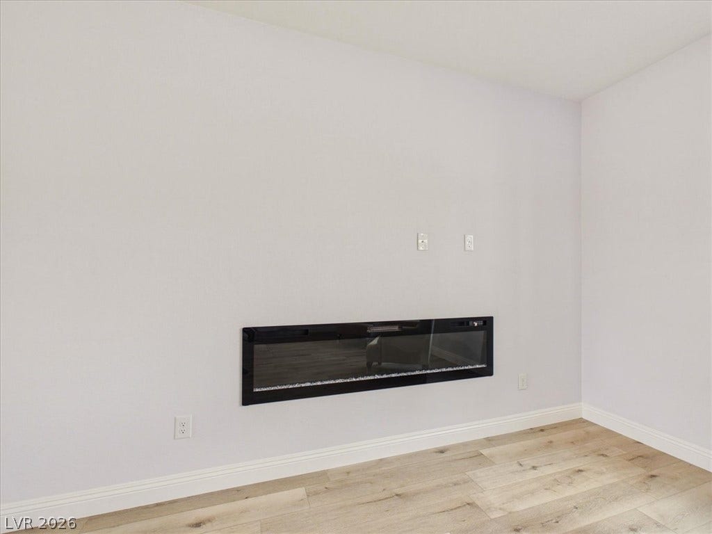 6680 S Raintree Court, Pahrump, NV 89061 A modern recessed fireplace anchors the crisp white walls and light wood-look flooring.