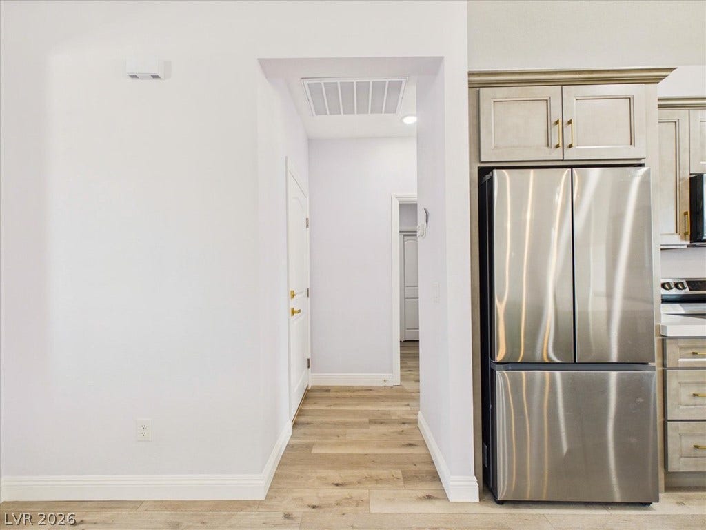 6680 S Raintree Court, Pahrump, NV 89061 Smooth wood-look flooring connects the bright hallway to a modern kitchen space.