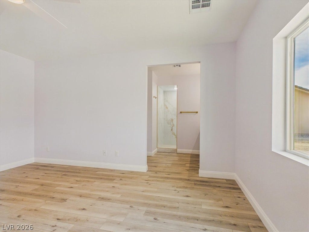 6680 S Raintree Court, Pahrump, NV 89061 Warm wood flooring and clean white walls create a serene and inviting bedroom retreat.
