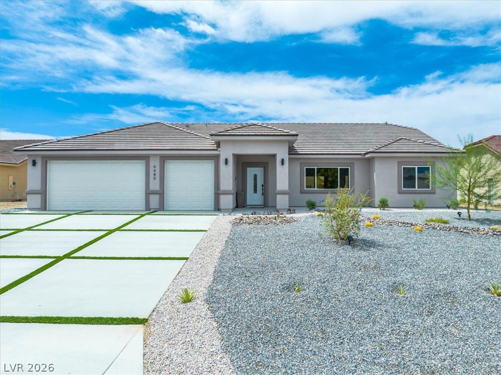 6680 S Raintree Court, Pahrump, NV 89061 A modern facade showcases clean architectural lines, a tile roof, and a low-maintenance gravel yard.