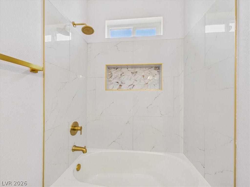 6680 S Raintree Court, Pahrump, NV 89061 Gleaming marble tile and gold hardware create a polished look in this bath.