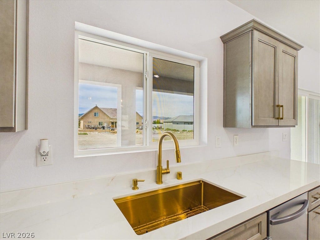 6680 S Raintree Court, Pahrump, NV 89061 A golden undermount sink sits beneath a kitchen window framed by classic cabinetry.