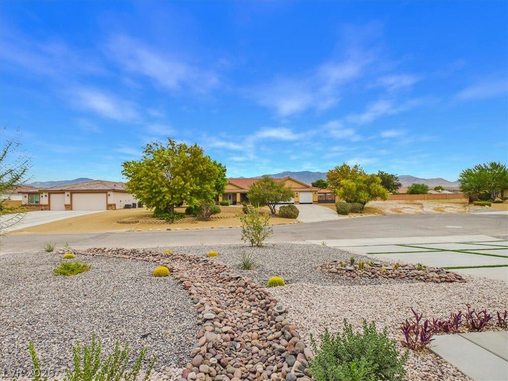 6680 S Raintree Court, Pahrump, NV 89061 Manicured desert landscaping frames a neighborhood view with distant mountain ranges under blue skies.