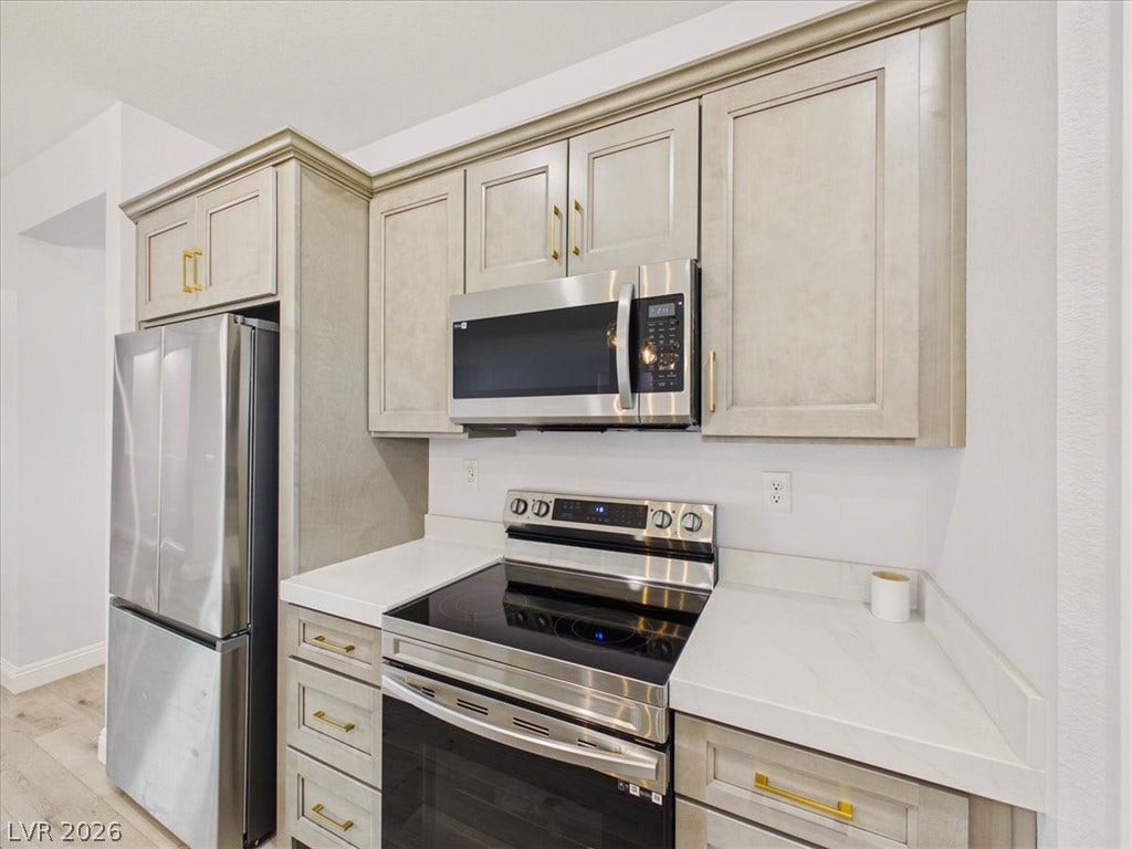 6680 S Raintree Court, Pahrump, NV 89061 Gleaming stone countertops and matching cabinetry surround modern kitchen appliances.