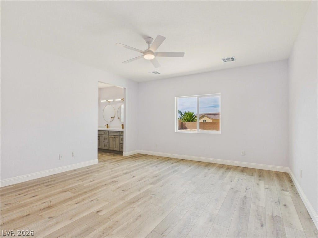 6680 S Raintree Court, Pahrump, NV 89061 Smooth wood floors and crisp white walls define this airy primary suite with an attached bath.