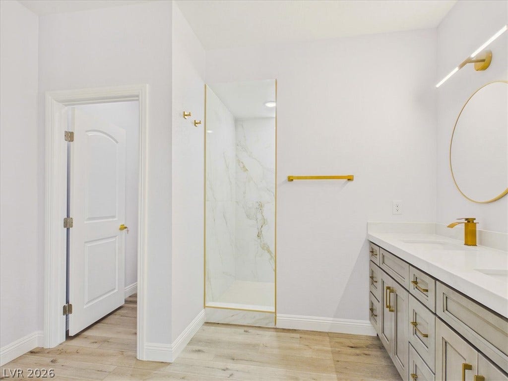 6680 S Raintree Court, Pahrump, NV 89061 Gleaming stone counters and modern gold fixtures elevate this serene bathroom design.