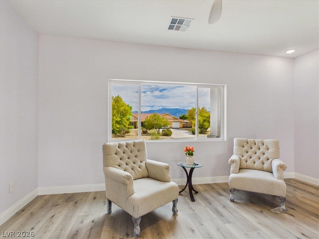 6680 S Raintree Court, Pahrump, NV 89061 A wide window frames picturesque mountain views in this inviting living space with light wood-style flooring.