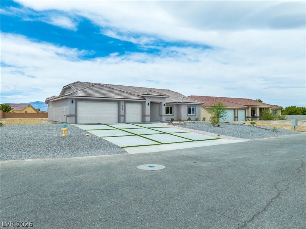 6680 S Raintree Court, Pahrump, NV 89061 Modern desert architecture frames this single-level residence with a geometric driveway and tile roof.