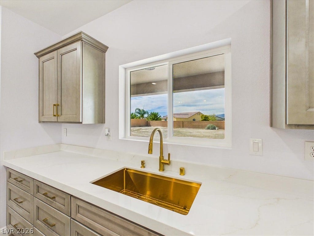 6680 S Raintree Court, Pahrump, NV 89061 An undermount sink with a gooseneck faucet centers a bright workspace beneath a large window.
