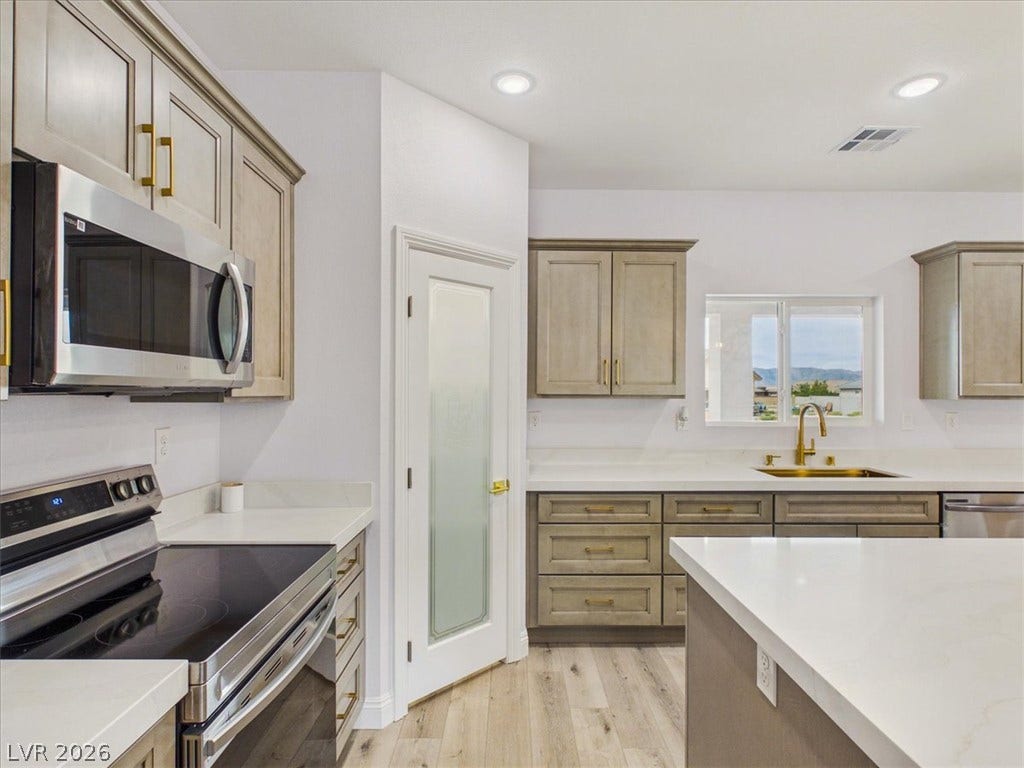6680 S Raintree Court, Pahrump, NV 89061 Warm wood cabinetry and pristine white countertops define this modern kitchen layout.
