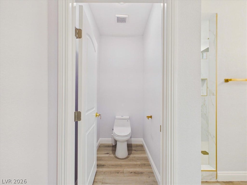6680 S Raintree Court, Pahrump, NV 89061 A private water closet showcases modern plank flooring and a classic white panel door.
