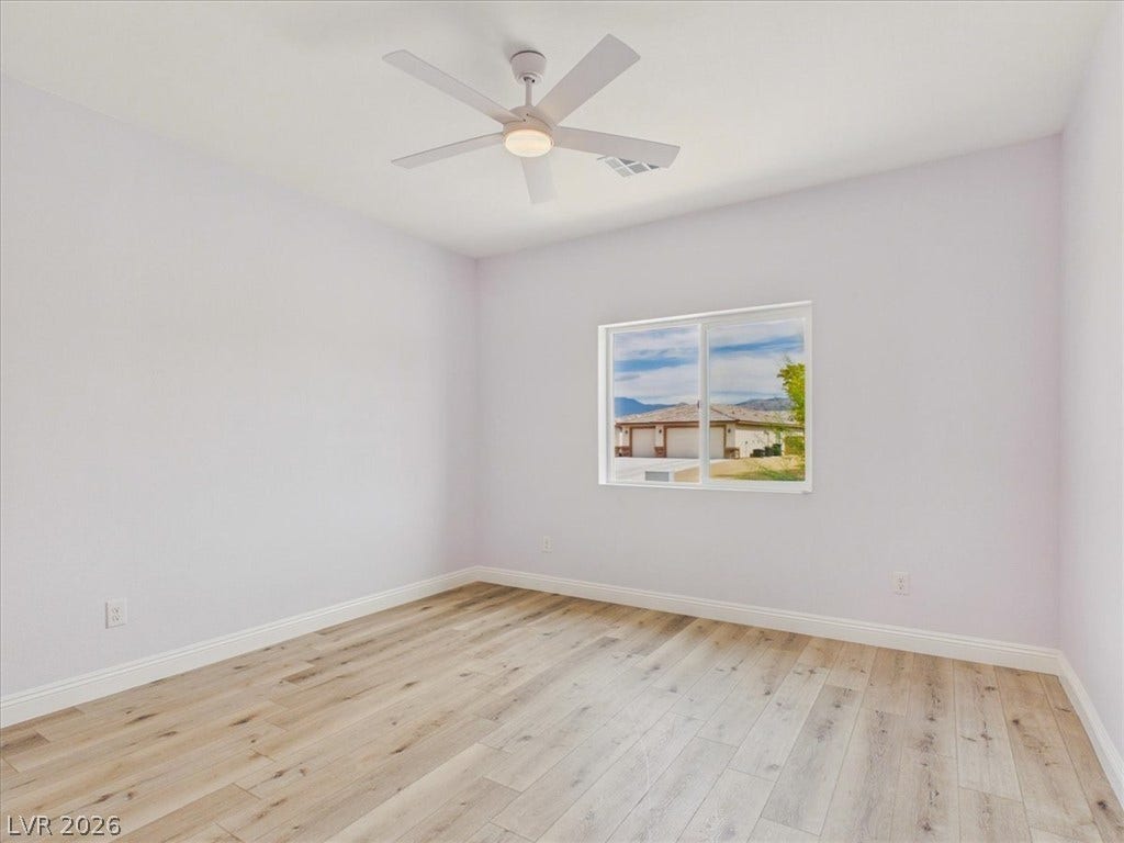 6680 S Raintree Court, Pahrump, NV 89061 Smooth wood floors and crisp baseboards anchor this clean, modern bedroom space.