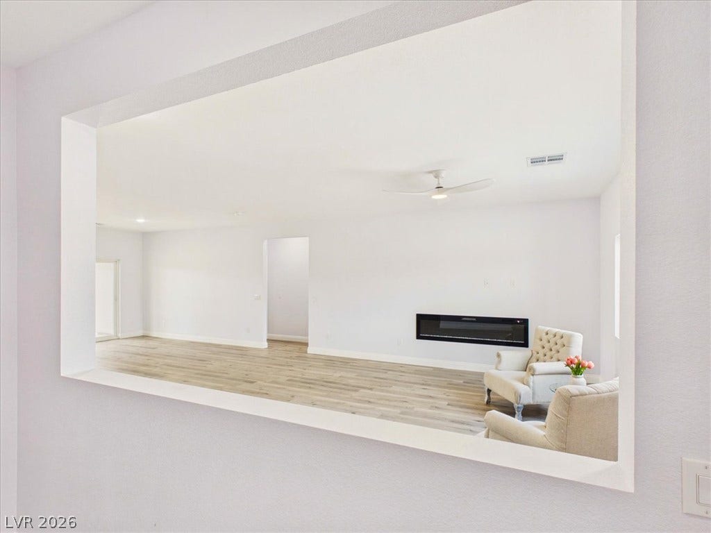 6680 S Raintree Court, Pahrump, NV 89061 An open floor plan framed by a wall cutout showcases hardwood flooring and a modern fireplace.