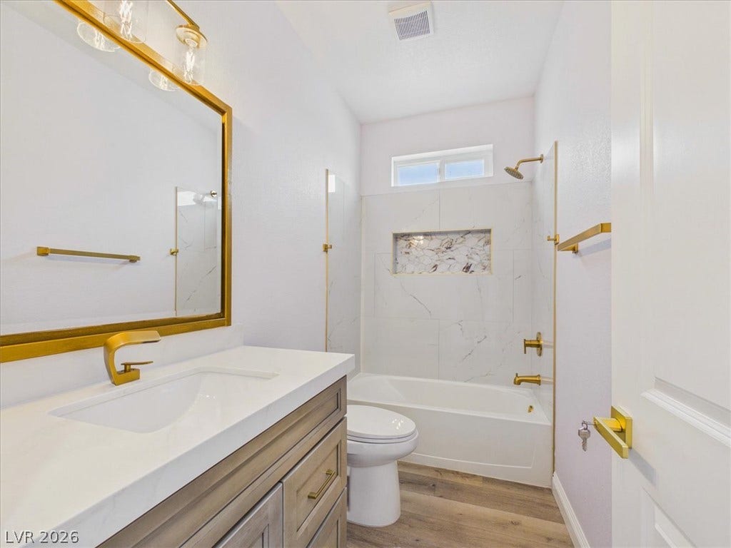 6680 S Raintree Court, Pahrump, NV 89061 Gleaming gold hardware accents this contemporary bathroom complete with a marble-tiled tub and shower.