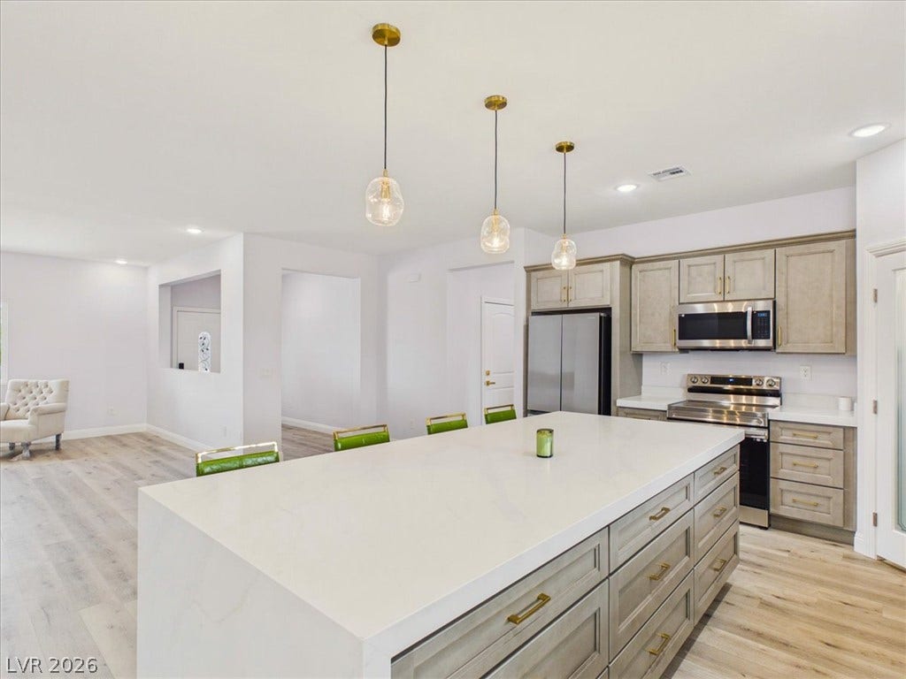 6680 S Raintree Court, Pahrump, NV 89061 An expansive central island anchors this contemporary culinary space with seamless wood-look flooring.