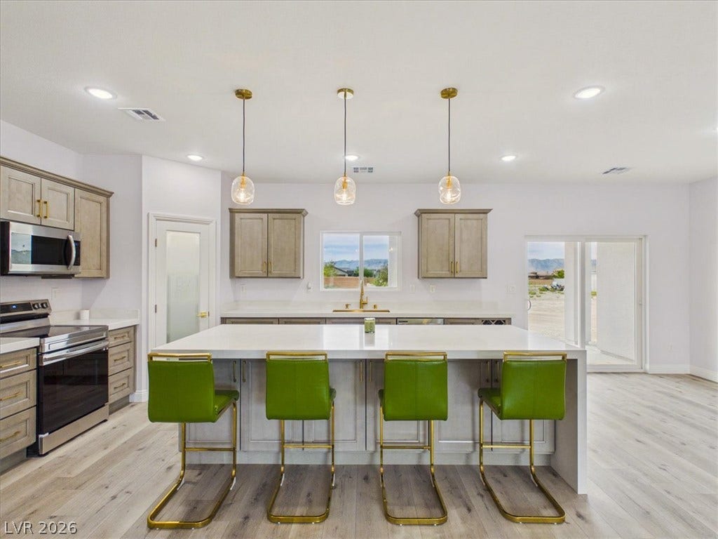 6680 S Raintree Court, Pahrump, NV 89061 Gleaming quartz countertops pair beautifully with light wood flooring in this modern kitchen.