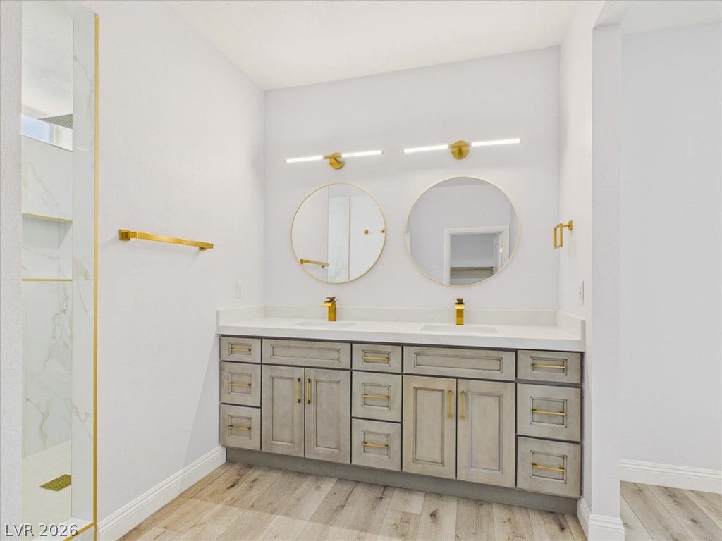 6680 S Raintree Court, Pahrump, NV 89061 Gold fixtures accent a dual vanity paired with wood floors.