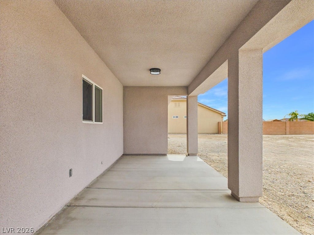 6680 S Raintree Court, Pahrump, NV 89061 A covered concrete patio provides shelter alongside the stucco exterior wall.