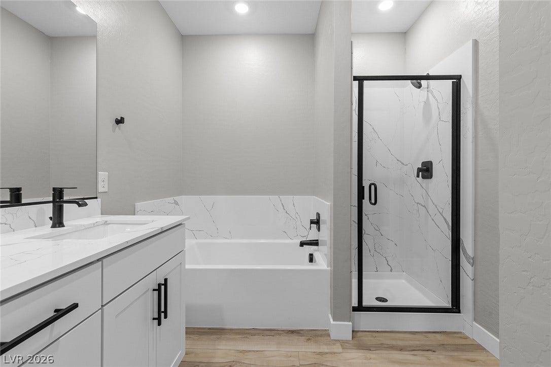 4608 Cave Lake Avenue, North Las Vegas, NV 89032 Clean lines and stone counters highlight this modern bathroom with a separate tub and shower.