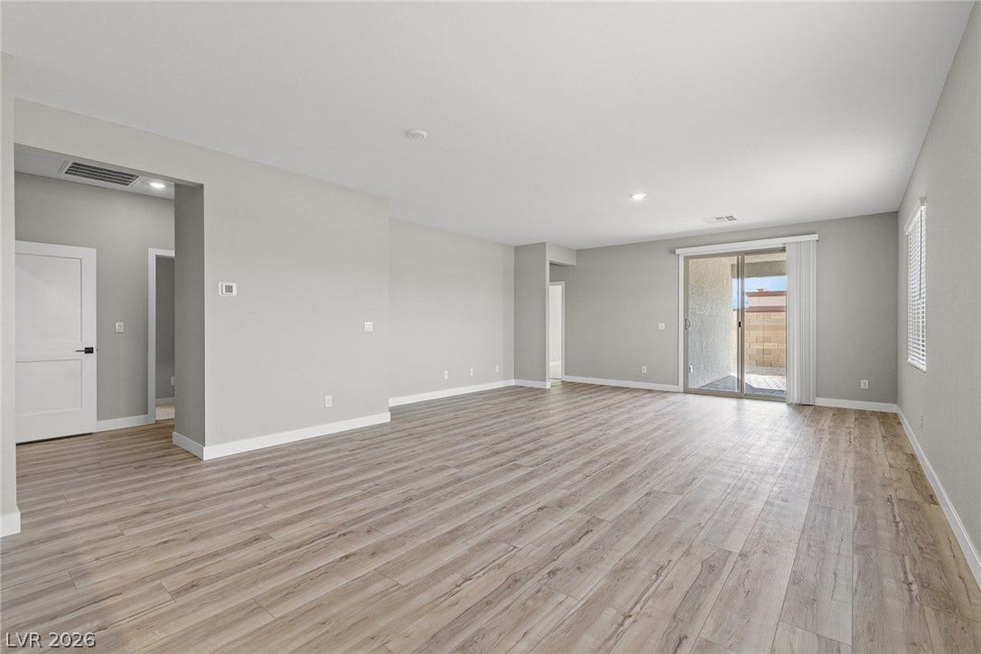 4608 Cave Lake Avenue, North Las Vegas, NV 89032 An open living area features wood-style flooring and sliding glass doors to the patio.