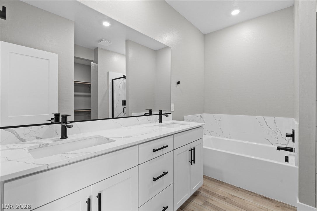 4608 Cave Lake Avenue, North Las Vegas, NV 89032 Clean lines and stone counters define this modern bathroom complete with a soaking tub.