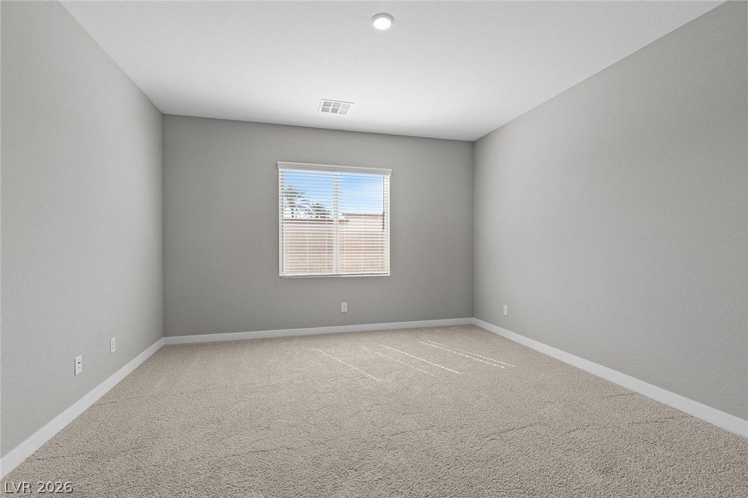 4608 Cave Lake Avenue, North Las Vegas, NV 89032 Plush carpeting and a wide window with integrated horizontal blinds define this serene bedroom space.
