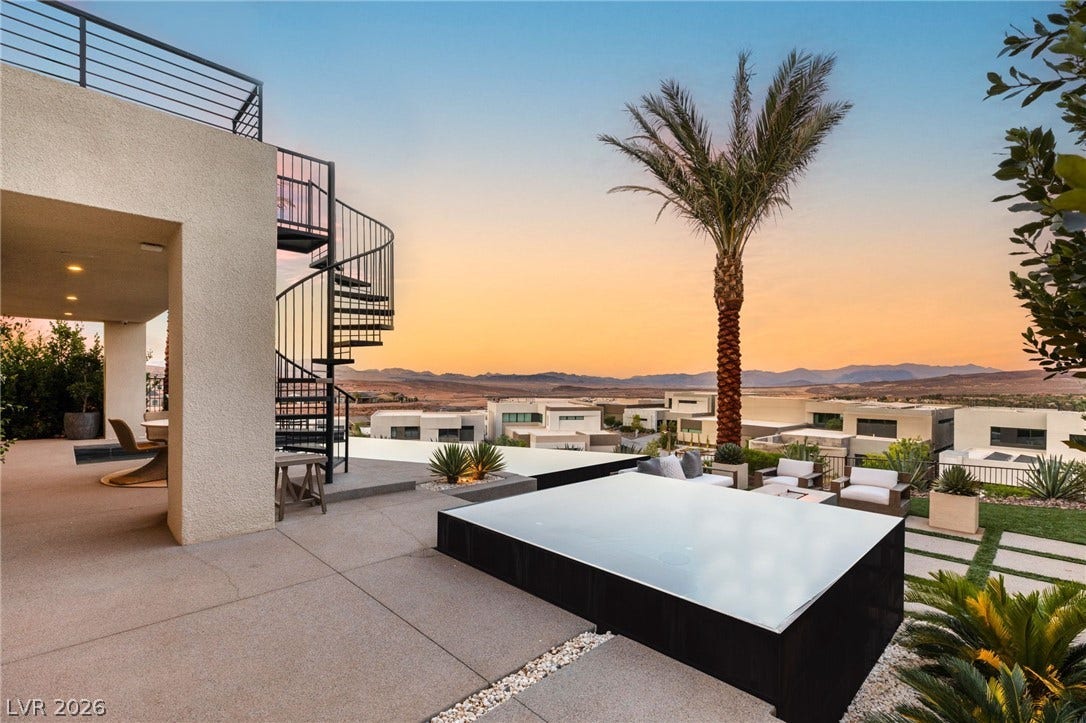 An outdoor patio with a stunning desert landscape and distant mountain view at sunset.