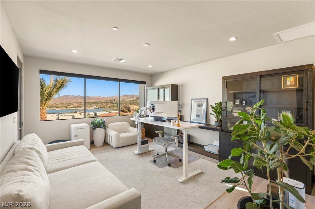 Floor-to-ceiling windows offer panoramic views of the distant mountains and glistening lake, creating an inspiring office space.