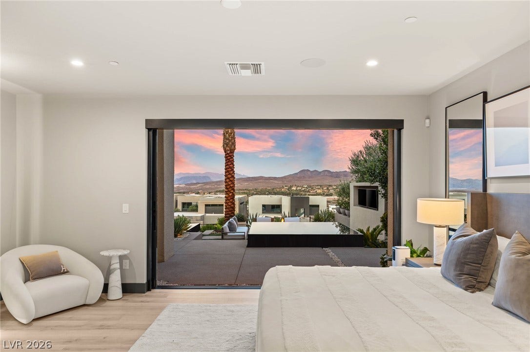 Retreat to a primary bedroom with direct access to a private patio, overlooking desert mountains.