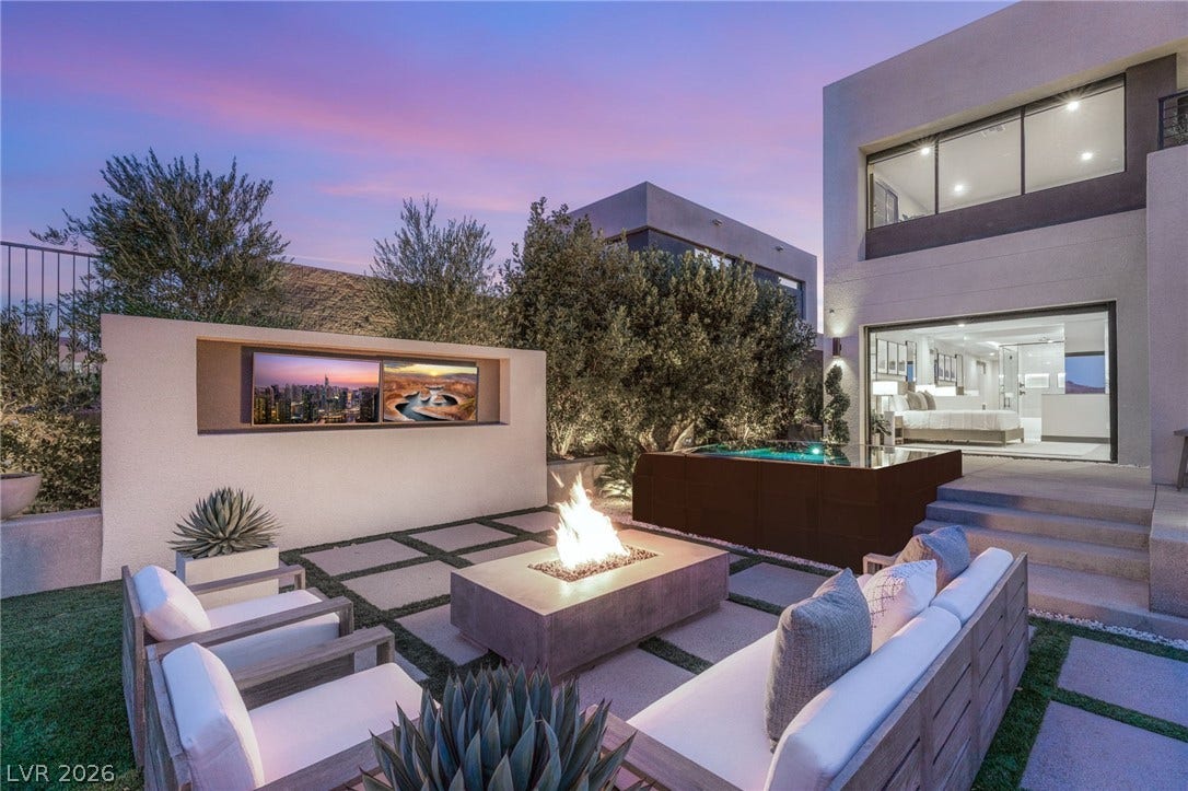 An inviting backyard retreat features a cozy fire pit, outdoor spa, and a built-in media center.