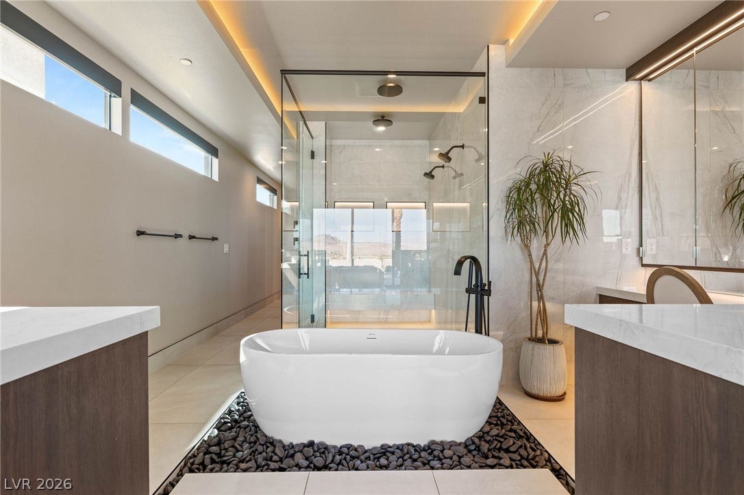 A spacious primary bathroom boasts a freestanding tub, glass-enclosed shower, and sleek vanity.