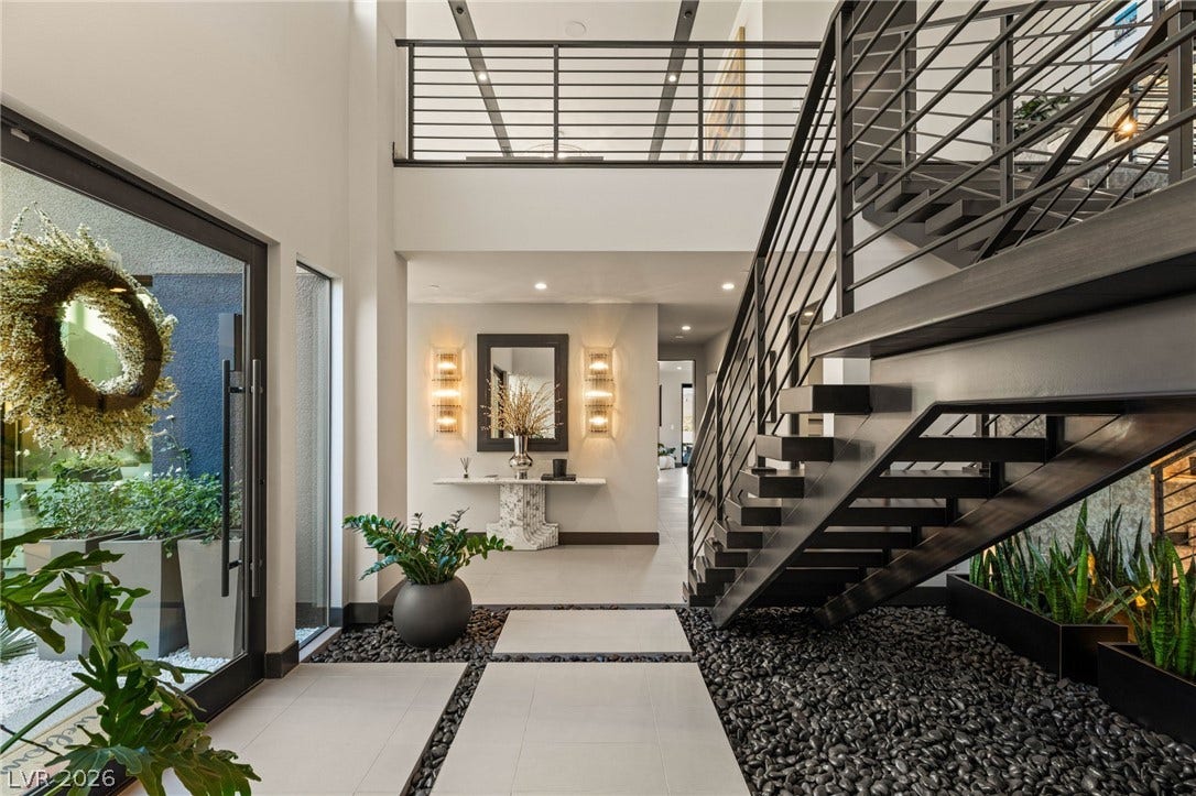 Enter into a soaring foyer with a striking modern staircase and sophisticated design elements.