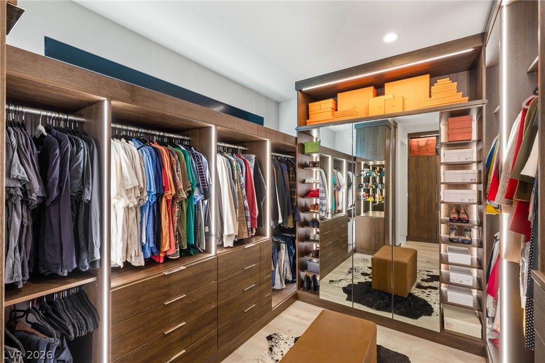 Ample storage solutions and thoughtful illumination define this meticulously organized dressing area.