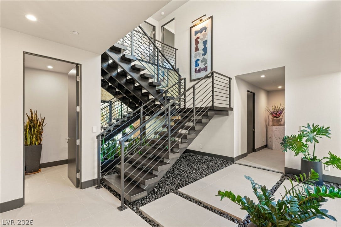 A grand, contemporary entry with a striking open-riser staircase and sleek metal railings.