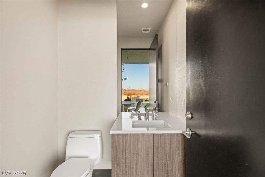 A well-lit contemporary bathroom features a pristine toilet and a sleek vanity with an outdoor view.