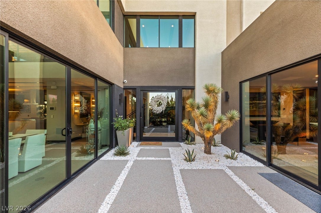 A modern facade with expansive glass doors creates an inviting entry, framed by desert landscaping.