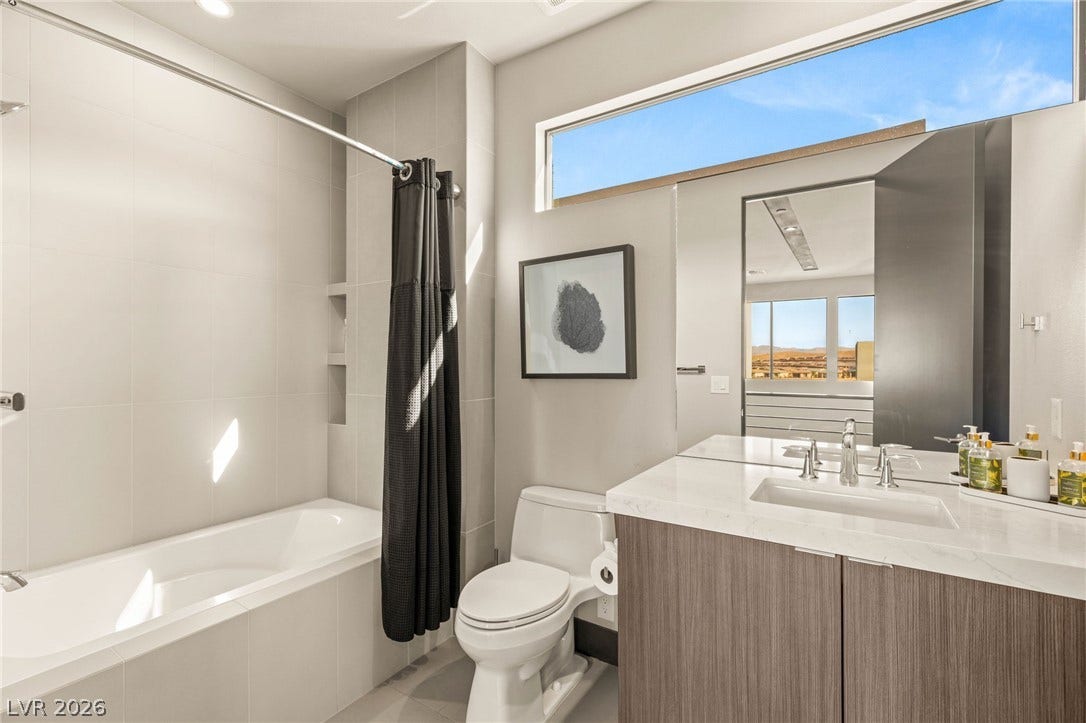 A sleek, contemporary bathroom with a pristine vanity and a serene soaking tub, bathed in natural light.