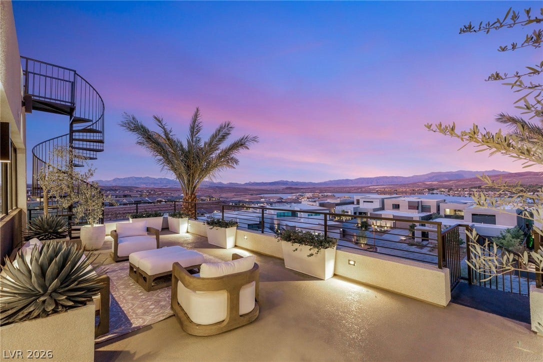An inviting rooftop deck offers unparalleled mountain and city light views under a vibrant sunset.