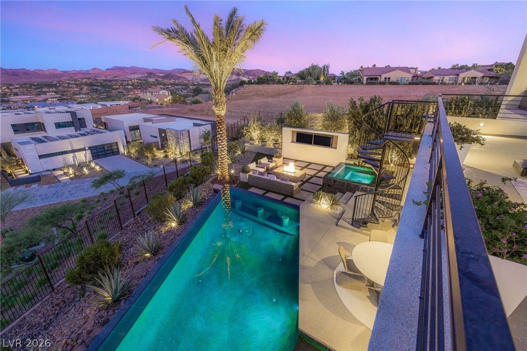 An evening panorama of an outdoor living space with a sparkling pool and breathtaking mountain views.