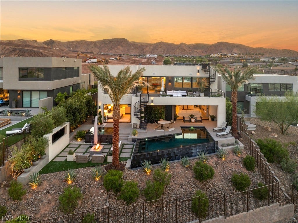 An aerial view reveals a grand home with a refreshing pool, fire pit, and ample space for outdoor enjoyment.
