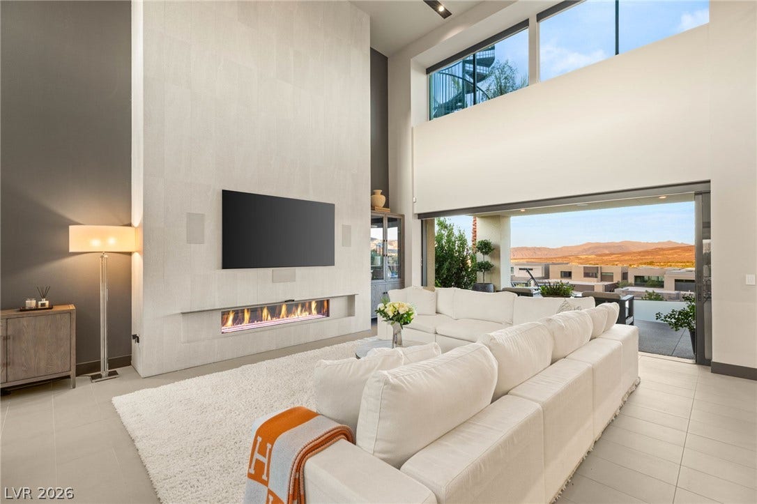 A striking fireplace wall and tall ceilings define this bright, modern living area with panoramic views.