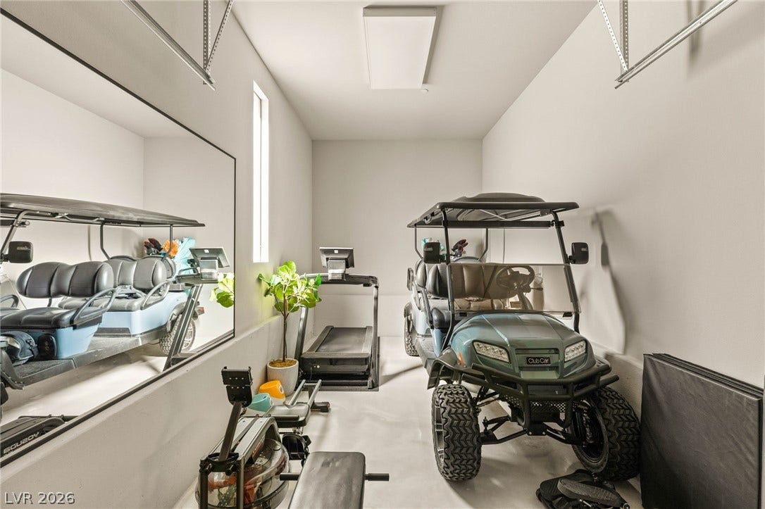 A well-organized garage space offers dedicated parking for a golf cart and an efficient home gym setup.