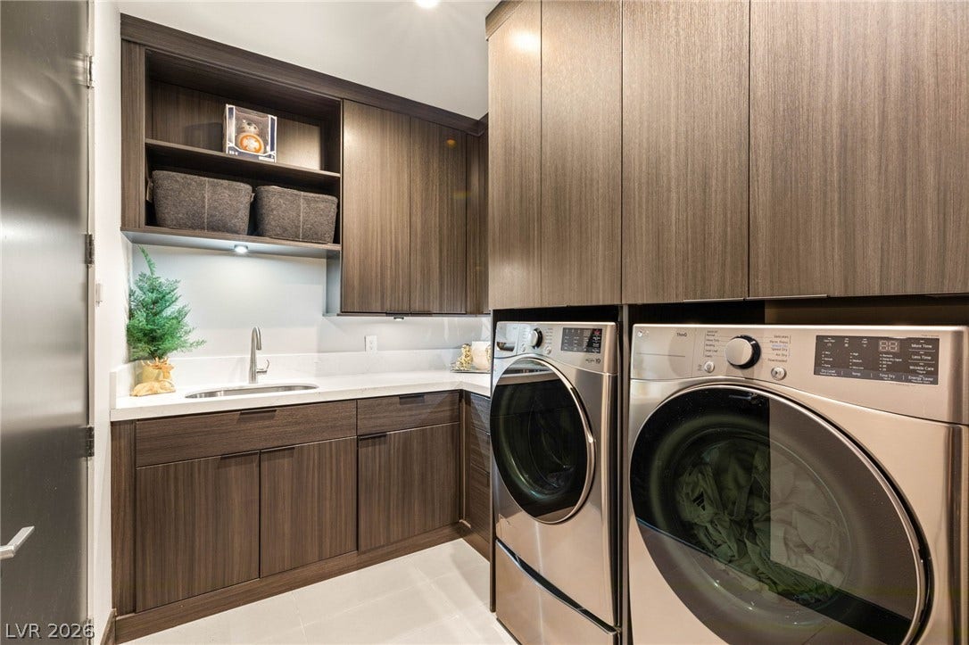 A streamlined laundry room provides functional design with extensive cabinetry and stainless steel appliances.